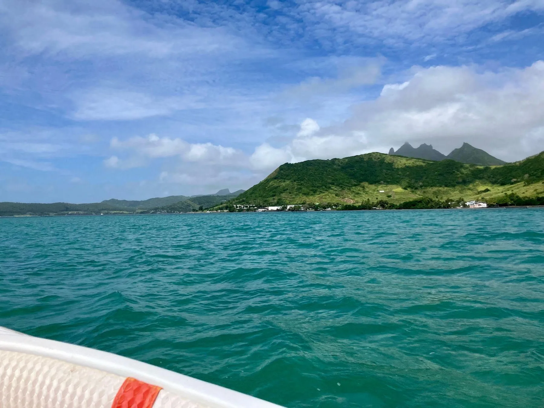 View from a boat across blue-green water toward Mauritius’s mountains